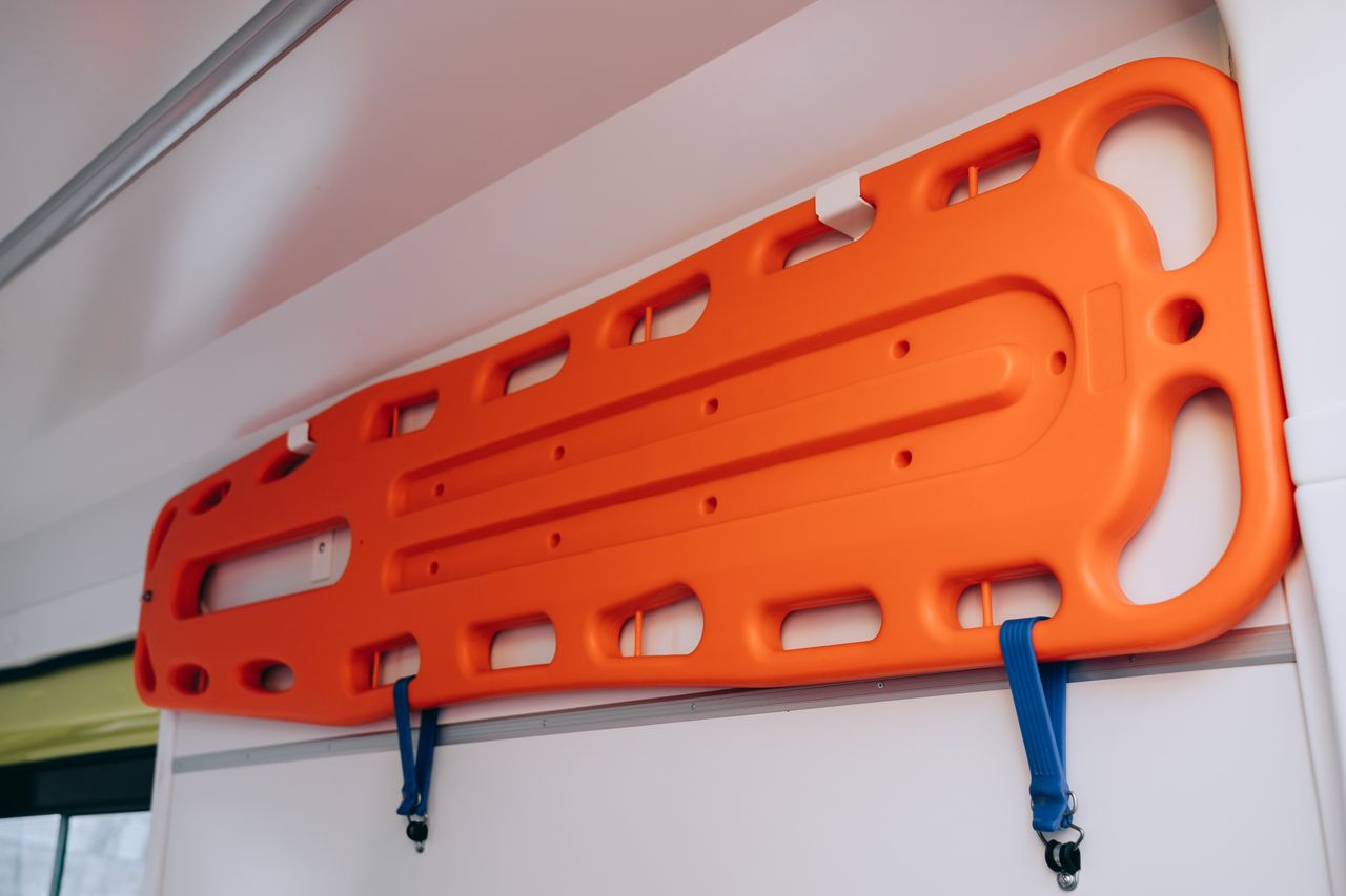 Close-up of an orange backboard stretcher mounted in an ambulance, ready for medical emergencies.