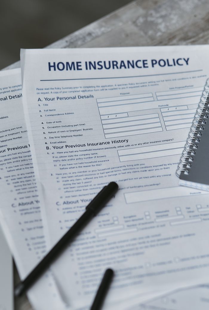 Flatlay image featuring a home insurance policy form and a notebook, shot from above.